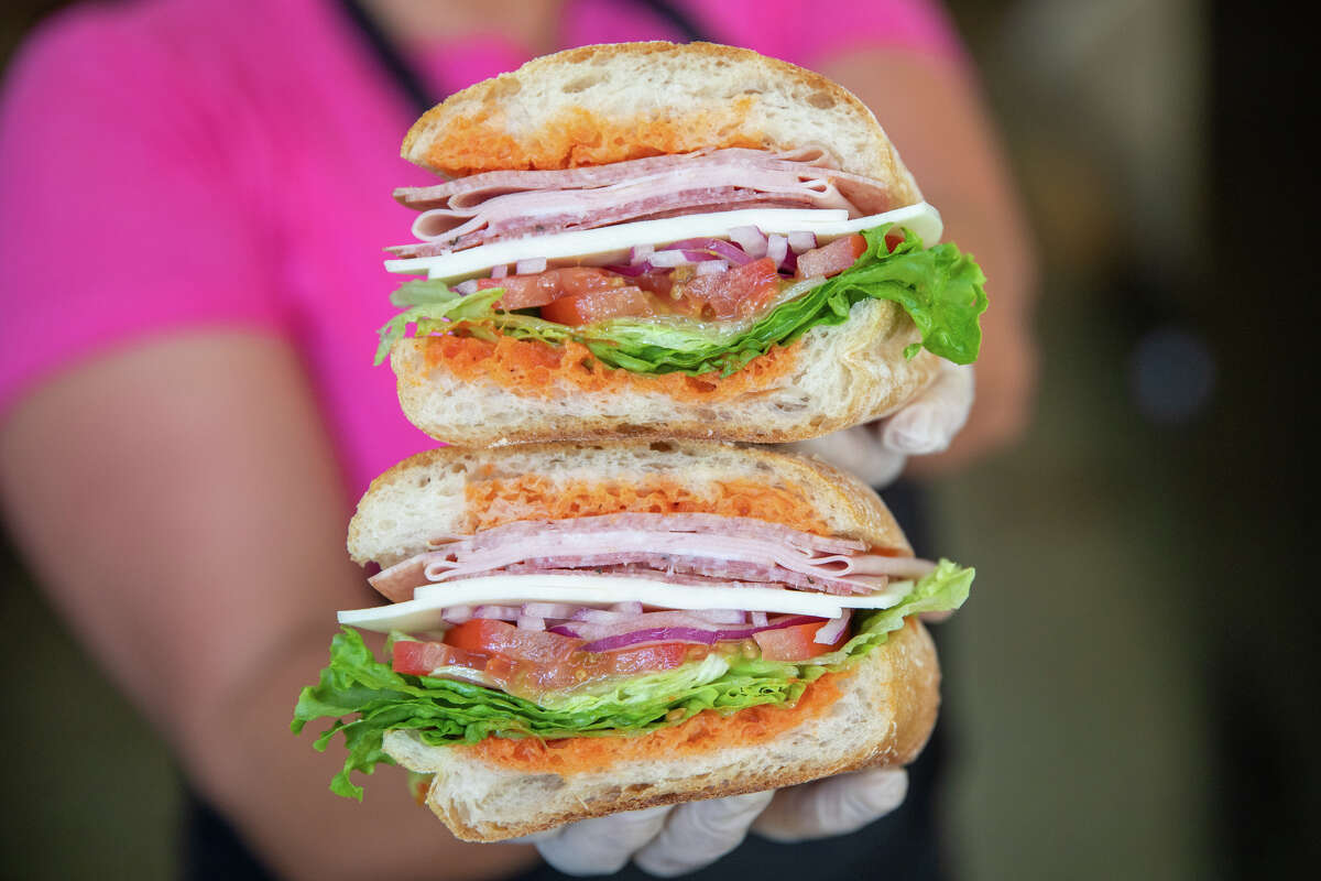 An employee holds up an Italian cold cut combo sandwich at Ratto's in Oakland, Calif., on Aug. 3, 2022.