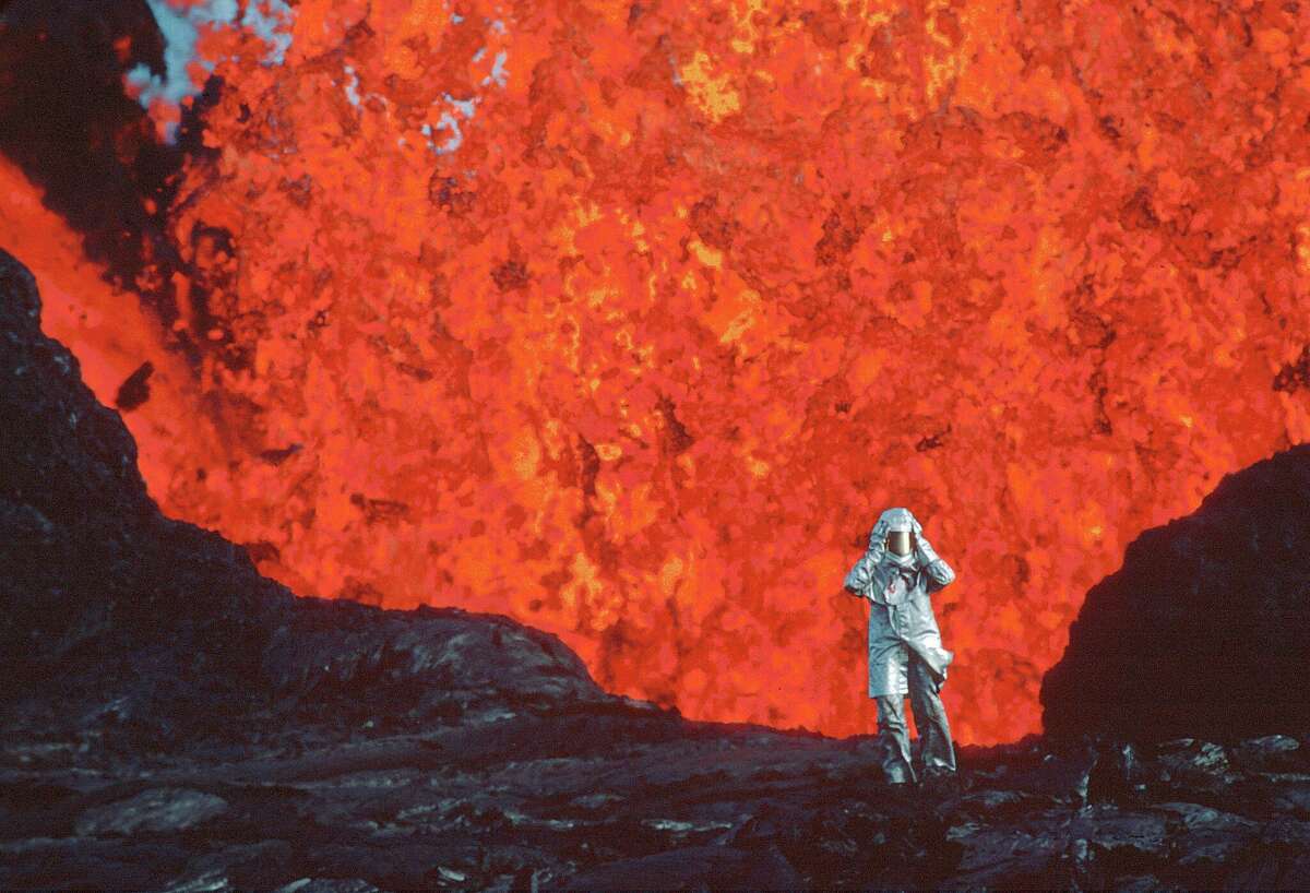 Katia Krafft wearing an aluminized suit standing near a lava burst at the Krafla Volcano in Iceland.