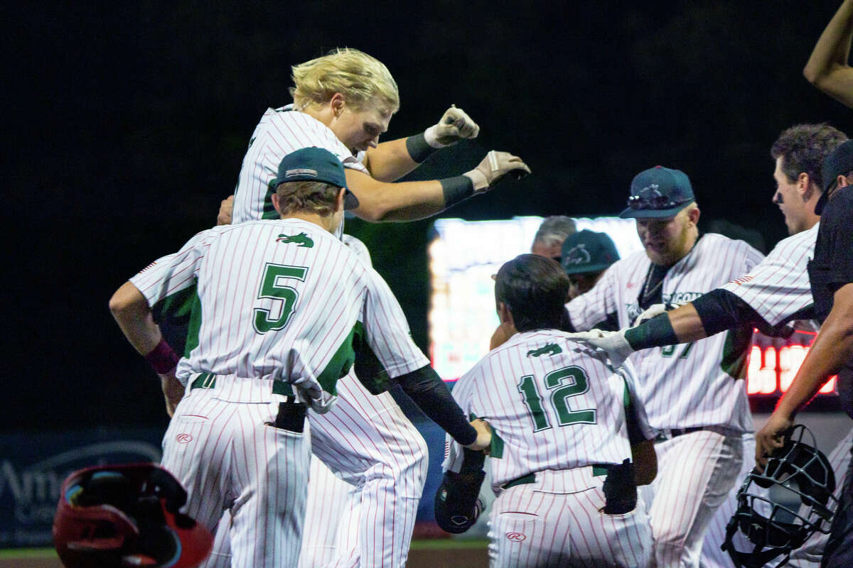 Erik Broekmeier is met by Alton river Dragons teammates at home plate after knocking a walk-off grand slam Tuesday to beat the Quincy Gems 8-7. 