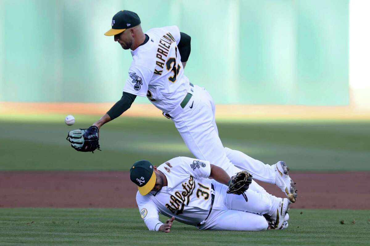 Oakland Athletics starting pitcher James Kaprielian (32) catches a popup by Los Angeles Angels' Jose Rojas as Vimael Machin (31) tries to get out of the way during the second inning of a baseball game in Oakland, Calif., Tuesday, Aug. 9, 2022. (AP Photo/Jed Jacobsohn)