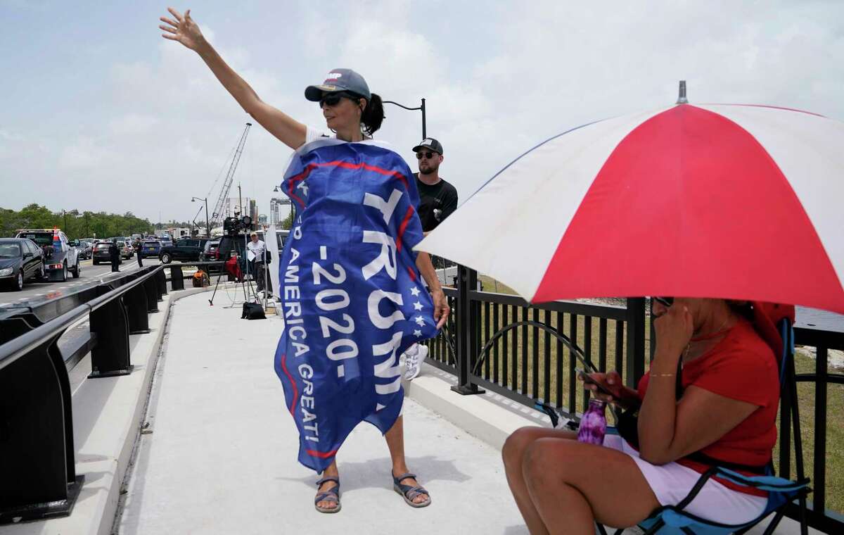 A Donald Trump supporter stands on a bridge outside the entrance to former President Donald Trump's Mar-a-Lago estate, Tuesday, Aug. 9, 2022, in Palm Beach, Fla. The FBI searched Trump's Mar-a-Lago estate as part of an investigation into whether he took classified records from the White House to his Florida residence, people familiar with the matter said Monday. (AP Photo/Lynne Sladky)