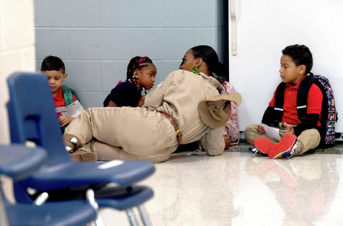 First-year pre-kindergarten teacher Kiara Woods lies down to talk with her students as they sit in the entry on the first day of school at Pietzsch - MacArthur Elementary in Beaumont. Photo made Wednesday, August 10, 2022. Kim Brent/The Enterprise