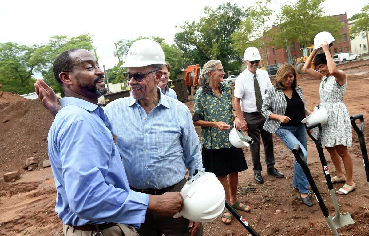 Darrell Brooks, chief of operations for Beulah Land Development Corporation, far left, and his father, Bishop Theodore Brooks, embrace during a ground breaking ceremony for a 69-unit affordable housing project on Dixwell Avenue in New Haven on August 9, 2022.