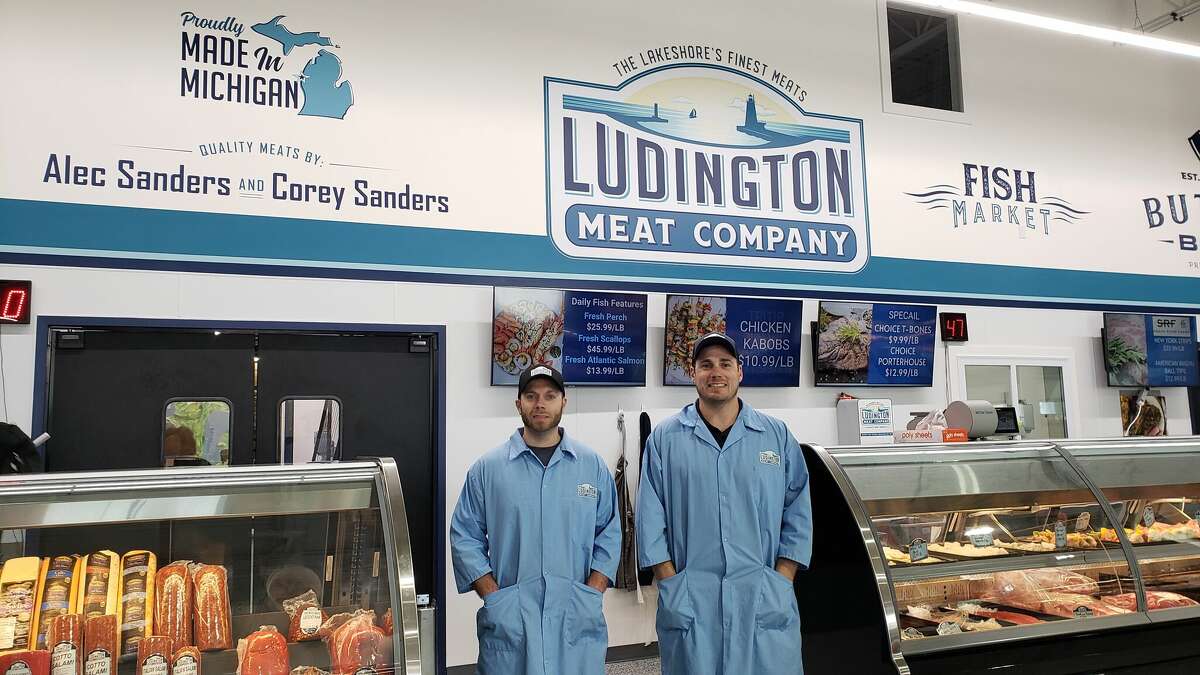 Ludington Meat Company owners Alec (left) and Corey Sanders stand at the meat counter inside their business.