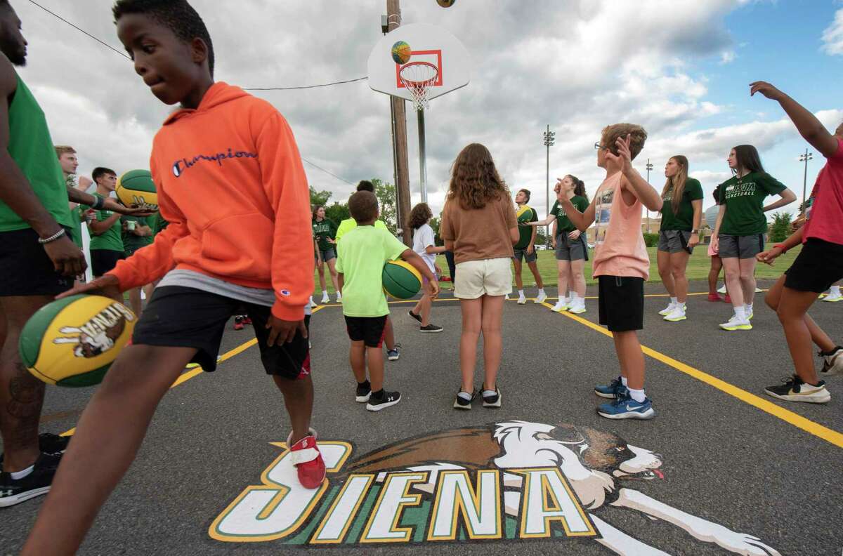 Kids play basketball with Siena players as Siena athletics hosts a court rehab dedication and ice cream social at Lansing Park on Wednesday, Aug. 10, 2022 in Cohoes, N.Y.