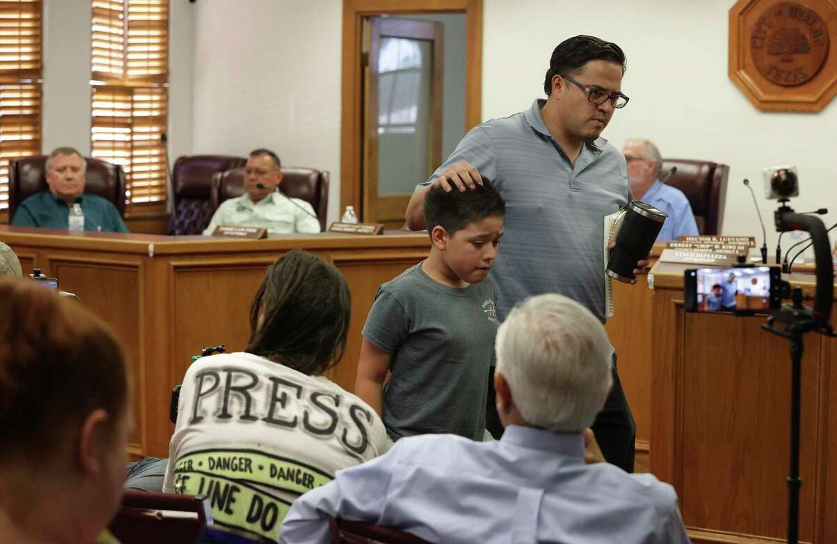 Uvalde resident Adam Martinez takes his son out the Uvalde City Council meeting Tuesday when a discussion gets too emotional. Several speakers from outside the city turned the council meeting more heated than usual.