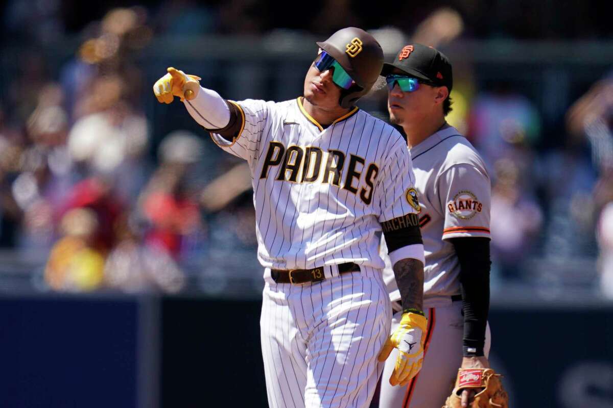 San Diego Padres' Manny Machado reacts after hitting a two-run double as San Francisco Giants second baseman Wilmer Flores looks on, right, during the third inning of a baseball game Wednesday, Aug. 10, 2022, in San Diego. (AP Photo/Gregory Bull)