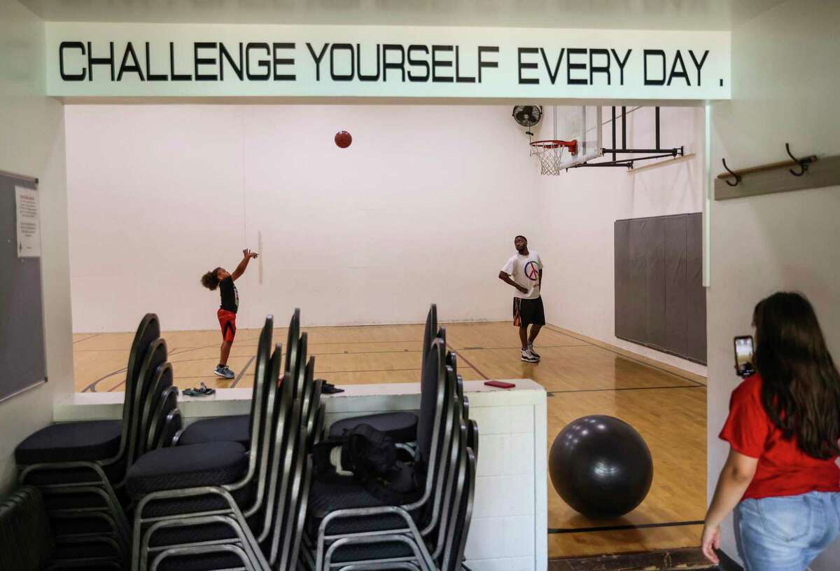 King Tari Johnson, 8, practices free throws as father Tari Johnson looks on and sister Celeste Wood shoots video of the session in Lodi.