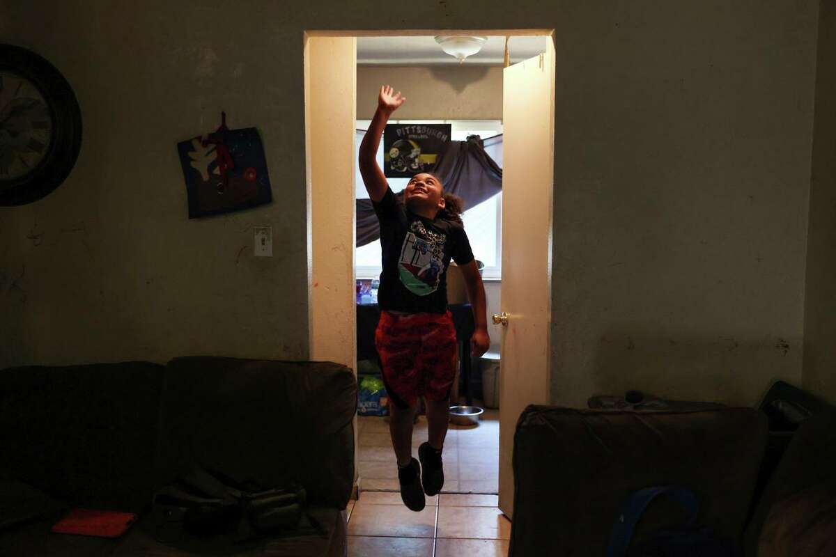 King Tari Johnson, 8, leaps up in a door frame in his house in Stockton. King Tari is the eighth-ranked 8-year-old basketball player in the nation.