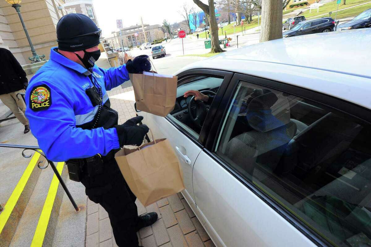 Bike Unit Officer Robert Smurlo helps deliver lunches during the Greenwich Senior Center's drive-thru service during the COVID-19 pandemic on March 19, 2021. Nearly 200 seniors were served. The Commission on Aging and Senior Center staff along with members of the police Bike Unit and other volunteers put the program together.