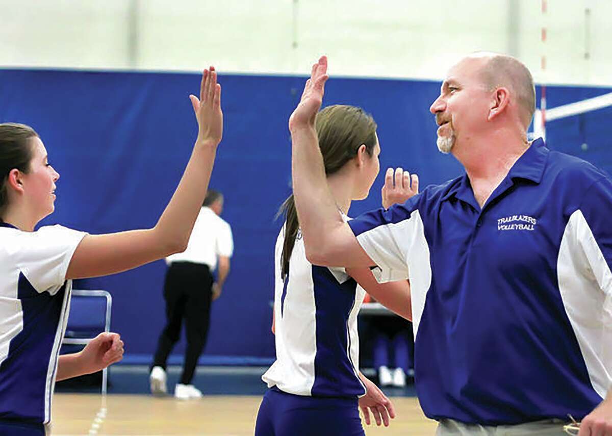Jim Hunstein high-fives with an LCCC volleyball player during 2013 action at the River Bend Arena. Hunstein, who coached LCCC volleyball and tennis from 2012 through 2015, has returned to the school and will coach the Trailblazers volleyball, men's tennis and women's tennis teams.