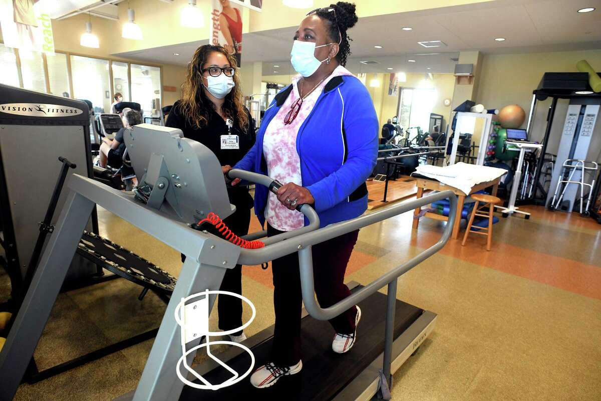 Pamela R. Lopes, of Woodbridge, a long term COVID patient, walks on a treadmill with physical therapist Emily Ponce-Calloway at Griffin Health’s physical therapy and rehabilitation facility in Derby, Conn. Aug. 10, 2022.
