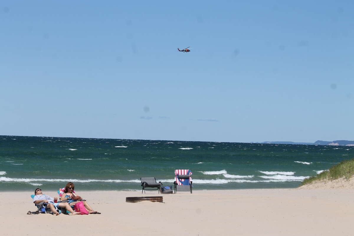 A U.S. Coast Guard helicopter flies over Lake Michigan at Fifth Avenue Beach in Manistee after a report was made of a capsized kayak in the water. It was later revealed the supposed kayak was actually a piece of dredging equipment near the pier.