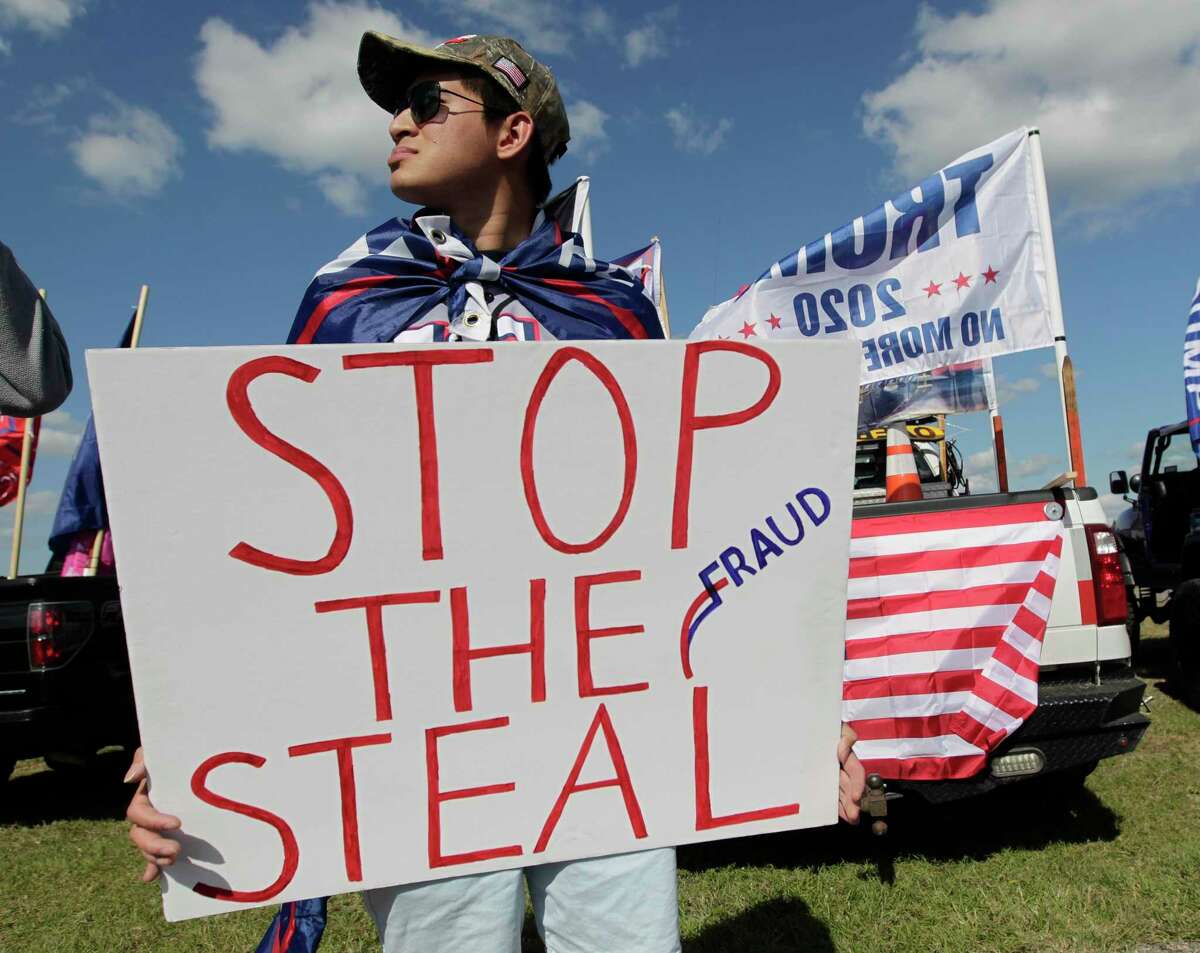 Elvis Van of Magnolia carries a “Stop the Steal” sign before a “Defend Our President” rally at the Montgomery County Fairgrounds, Saturday, Nov. 7, 2020, in Conroe.