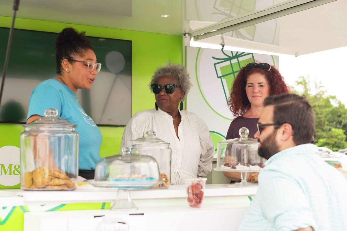 Janaya Young, state Sen. Marilyn Moore and Leisha Young, owner of Leisha’s Bakeria chat with a customer at the M&T Bank pop up shop at Captain’s Cove Seaport in Bridgeport, Conn. on Aug. 11, 2022