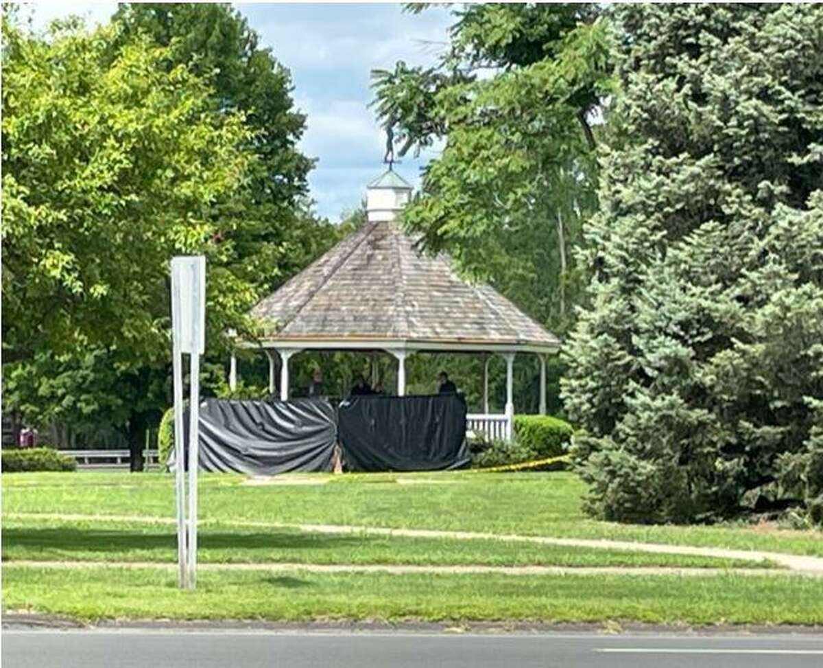 Police work in a gazebo on the town green in Enfield, where a dead body was found early Wednesday.
