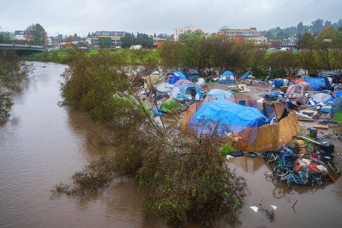 Bloated by heavy rains, the San Lorenzo River partially floods a homeless encampment at Riverwalk Park in Santa Cruz.