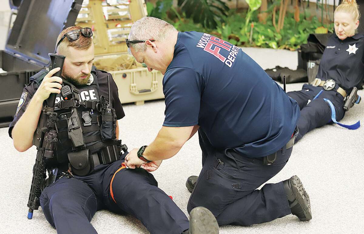 John Badman|The Telegraph A Wood River firefighter applies a tourniquet to the leg of a police officer during the active shooter training Thursday.