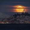The last supermoon of 2022 is seen rising over Coit Tower in San Francisco, Calif.