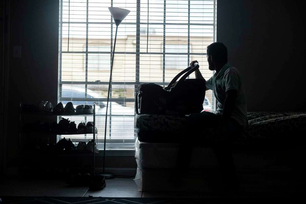 Aziz, an Afghan living in the Houston area, sits in his home with with a carseat for his new baby on Thursday, July 28, 2022.