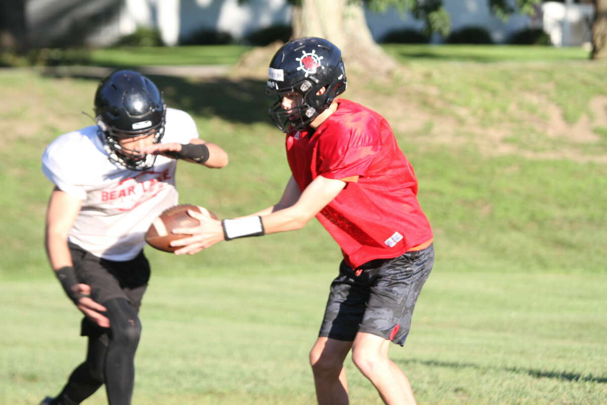 A quarterback hands the ball off to a running back