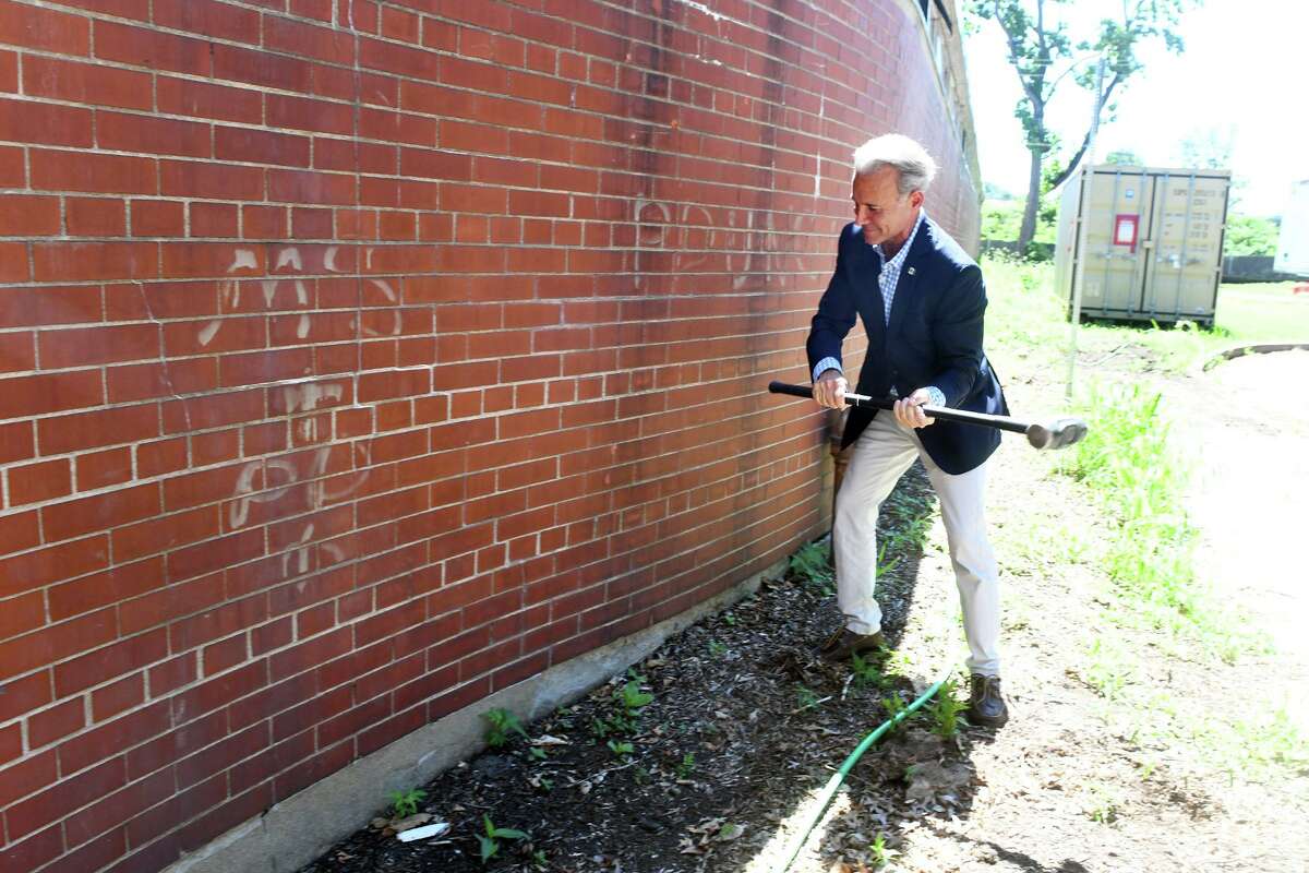 First Selectman Fred Camillo takes a swing with a sledgehammer to an exterior wall during a final visit to the Greenwich Civic Center on Friday. The building will be demolished in the coming months.