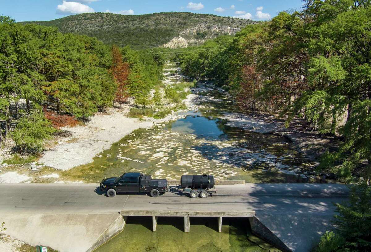 A pickup truck pulls a water tank across the nearly dry Frio River in Concan on Aug. 10. Restrictions imposed by the Concan Water Supply Corp. to reduce water use have forced customers to find other sources of water for nonessential uses, such as filling swimming pools. Drought has caused most of the wells for the community’s public water supply to go dry and put it at risk of running out of water in 45 days, according to the Texas Commission on Environmental Quality website.