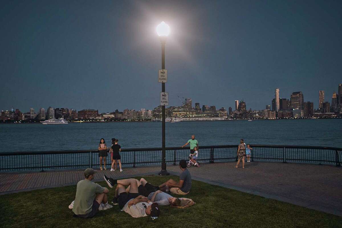 FILE - People spend time at the park at dusk during a summer heat wave, July 21, 2022, in Hoboken, N.J. The continental United States in July set a record for overnight warmth, providing little relief from the day’s sizzling heat for people, animals, plants and the electric grid, meteorologists said.