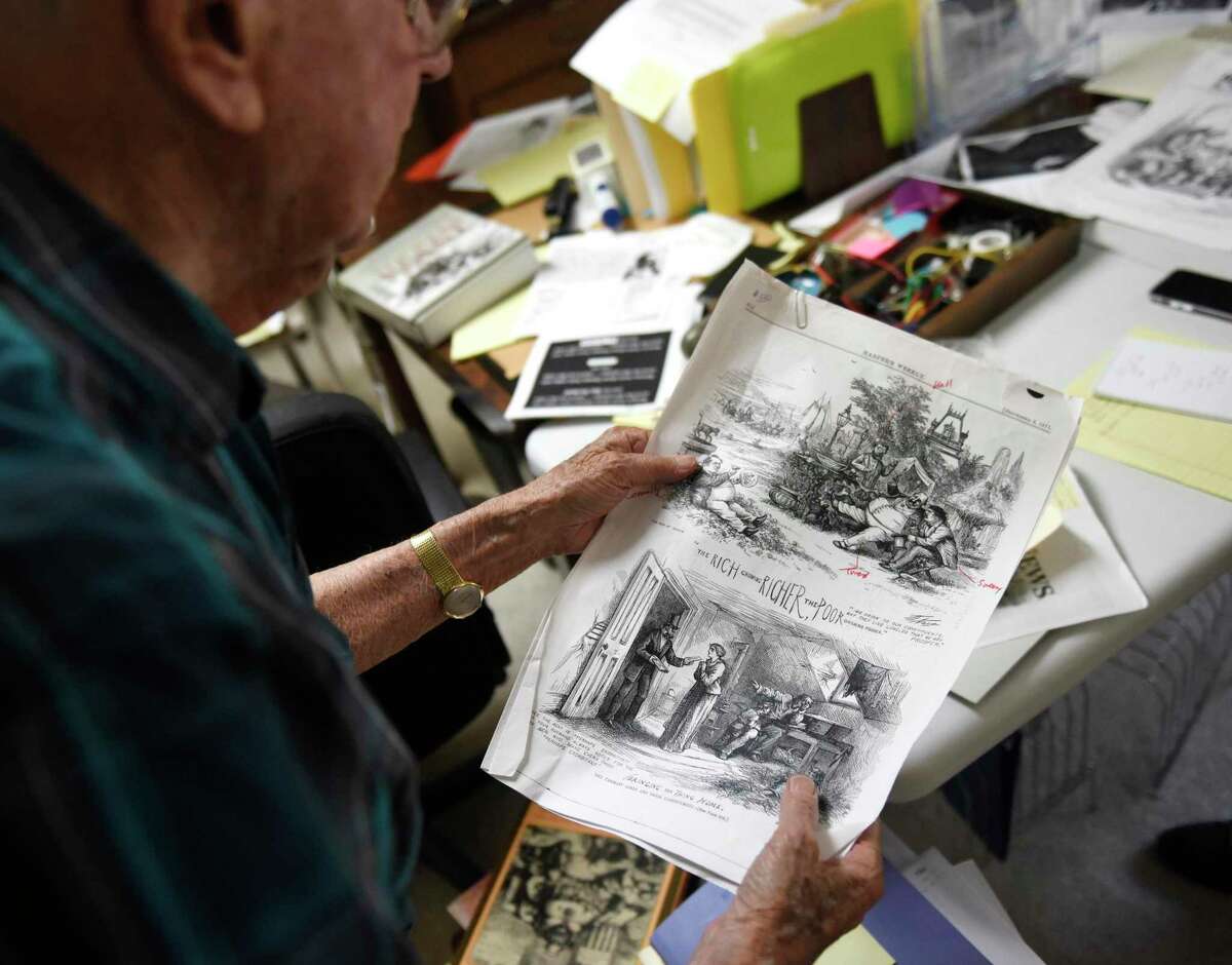 Author John Adler, 94, shows a political cartoon depicting a scene in Greenwich by Thomas Nast at his home in the Riverside section of Greenwich, Conn. Monday, Aug. 8, 2022. Adler has a forthcoming book titled "America's Most Influential Journalist: The Life, Times and Legacy of Thomas Nast" about the life and work of pioneering political cartoonist, Thomas Nast, and owns substantial collection of Nast's work.