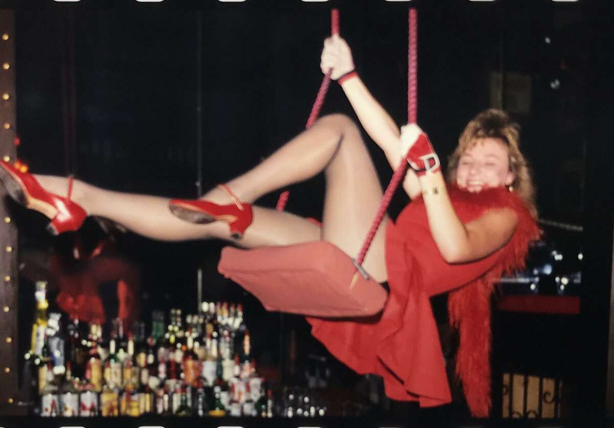 Costumed as a turn-of-the-last-century dance-hall performer, a “Girl in the Red Velvet Swing” working at the Old San Francisco Steak House attempts to ring the cowbell hung above the bar. The memorable entertainment captivated audiences for nearly 40 years.