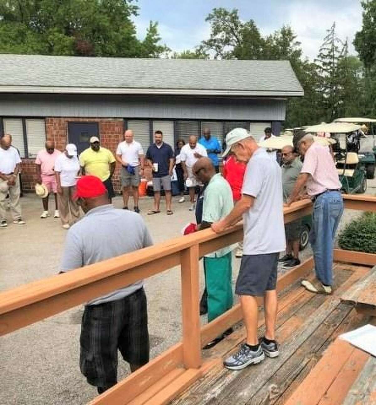 At a past tournament, participants in the Alton Black Alumni Reunion  Lee C. Cox Memorial Scholarship Golf Tournament bow their heads in prayer before the start of a tournament.