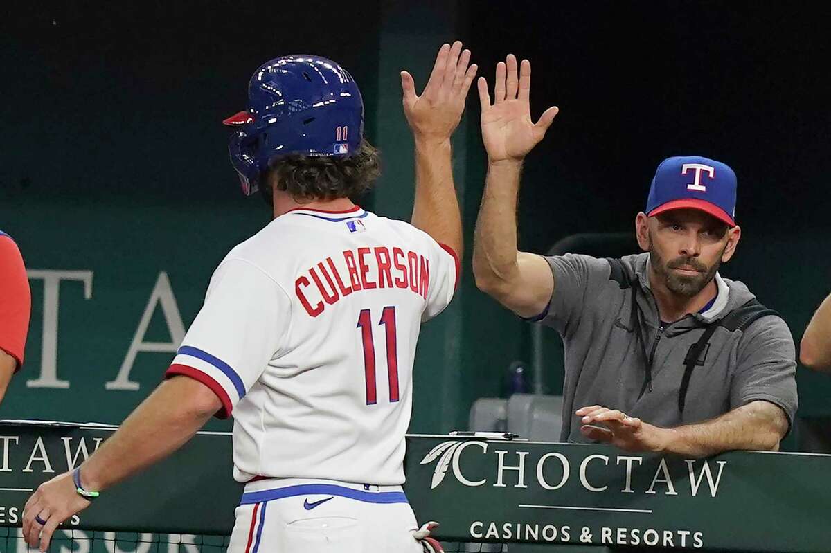 Texas Rangers' Charlie Culberson (11) gets a high five from manager Chris Woodward after scored on a sacrifice bunt by teammate Bubba Thompson during the fourth inning of a baseball game against the Seattle Mariners in Arlington, Texas, Saturday, Aug. 13, 2022.