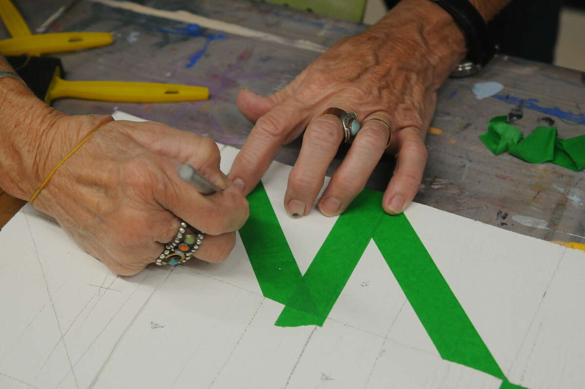 A barn quilt class participant carefully tapes down a pattern during a Macoupin Art Collective class on Saturday.