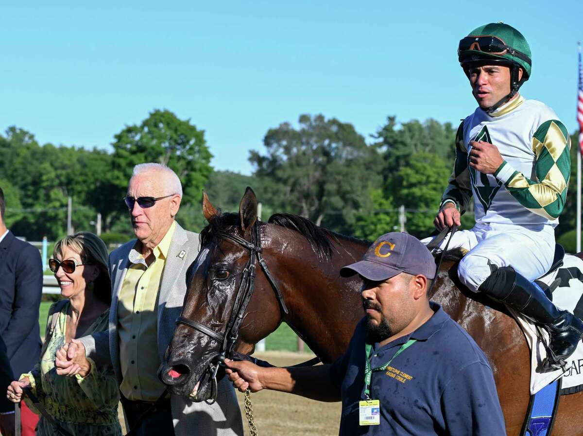 Jockey Joel Rosario is all smiles as he is lead to the winner's circle on Big Invasion by Dean Reeves, second from left and his wife Patti after winning the 4th running of The Mahony at the Saratoga Race Course Sunday Aug. 14, 2022 in Saratoga Springs N.Y. Photo Special to the Times Union by Skip Dickstein