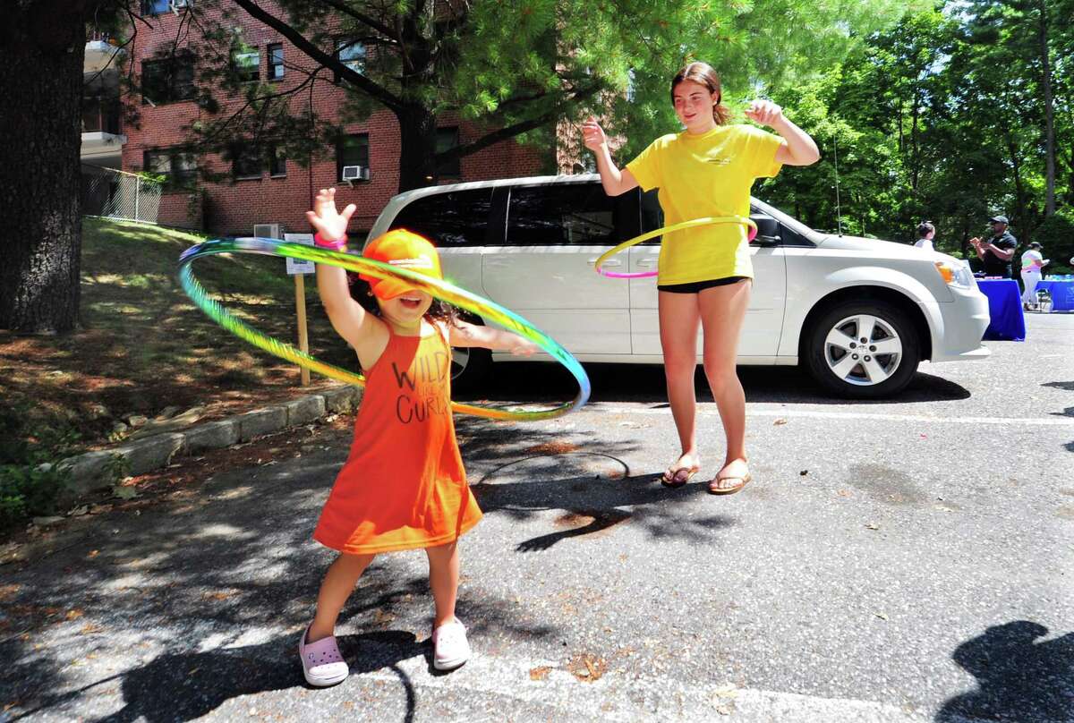 Lila Braddock, in back, teaches Chloe Ortiz, 3, how to use a hula hoop during Family Centers Health Care clinic's annual Community Health Fair at Wilbur Peck Court in Greenwich on Saturday.