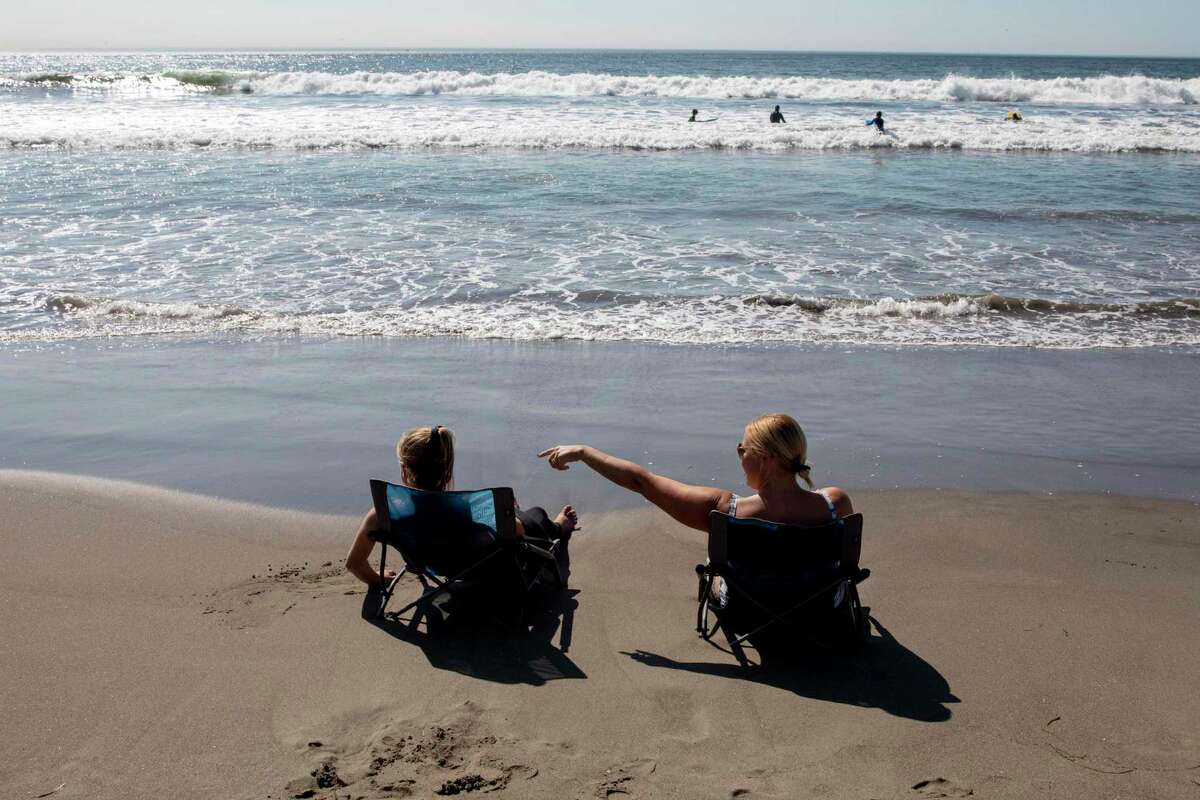 Catherine Reese and her daughter Addison, 12, both visiting from Vancouver, Washington sit on beach chairs in Stinson Beach, Calif. A heat wave was expected to bring a blast of hot weather, and triple-digit temperatures, to parts of the Bay Area.