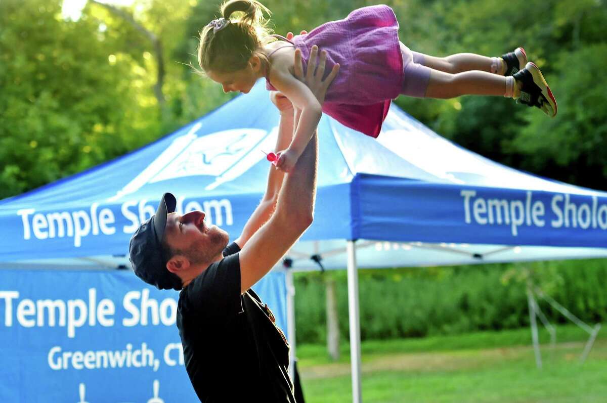 Andrew Levy swings his daughter Mae, 2, into the air during Temple Sholom's Shabbat on the Sound at Tod's Point Park in Greenwich on Friday. The event started with a Young Family Shabbat for kids and then a Musical Shabbat for all ages afterwards.