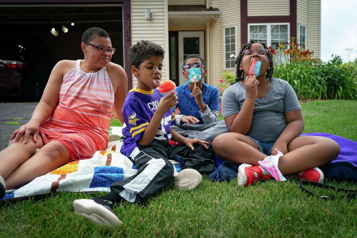 Sheletta Brundridge sits with her three youngest children, Daniel, 7, Brandon, 10 and Cameron, 9, after an ice cream truck came by the house, Wednesday, July 27, 2022, in Cottage Grove, MN. Sheletta Brundridge moved her family, including her three children who had been diagnosed with autism, from Texas to Minnesota in order to access more social and educational services for the kids.