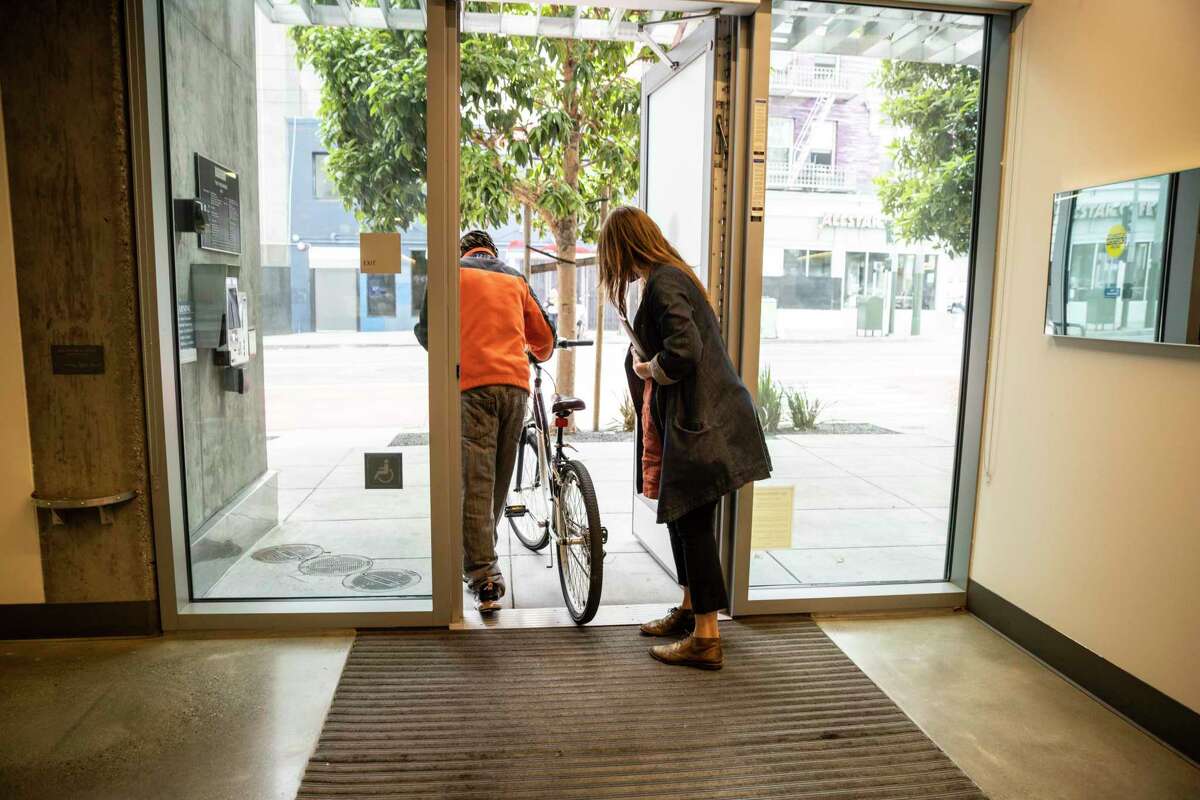 Lauren Hall, director and co-founder of Delivering Innovation in Supportive Housing, helps a resident with the door at the Panoramic Hotel.