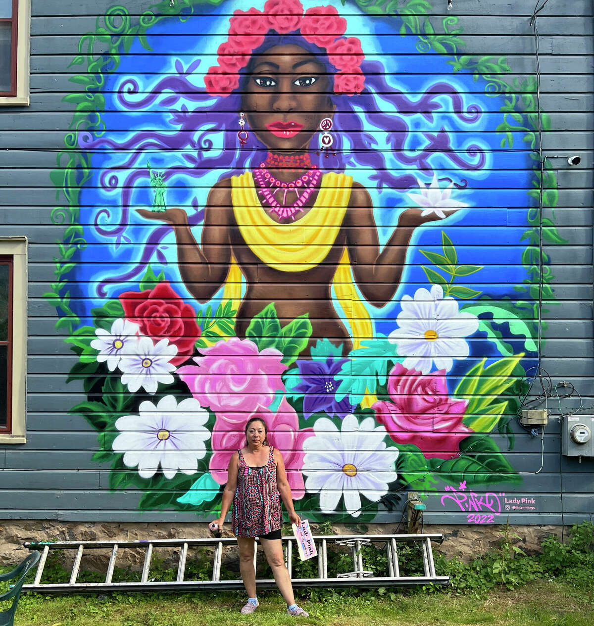 Lady Pink pictured with her design for the Roses for Rosendale mural project. This mural was done on the backside of the Garden House.