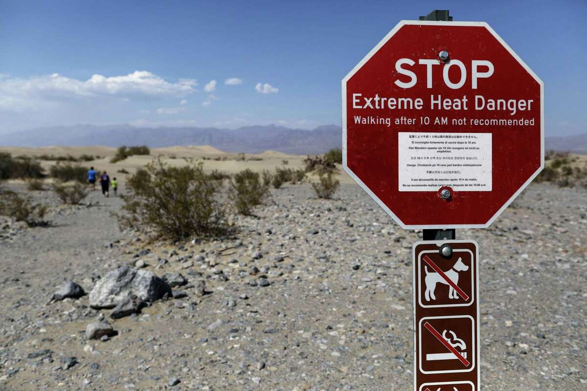 2020年，在死亡谷国家公园，游客们走过一个警告极端高温危险的标志。