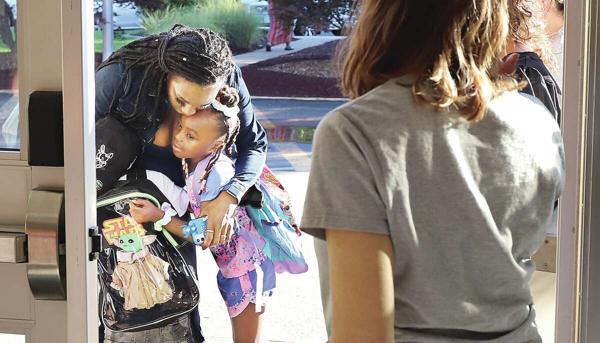 A mother hugs her children at the front door of Gilson Brown School in Godfrey Wednesday before they started their first day of school. Parents were asked not to come into the school on the first day to make the transition smoother for first time students. Lots of staff were on hand to help all of the children figure out where they were supposed to be.
