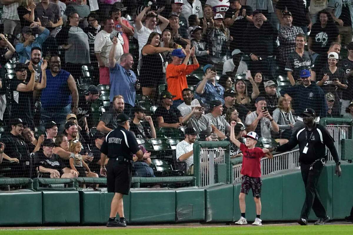 An unidentified boy is escorted off the field after entering in center during the ninth inning of a baseball game between the Chicago White Sox and the Houston Astros Wednesday, Aug. 17, 2022, in Chicago. The Astros won 3-2. (AP Photo/Charles Rex Arbogast)