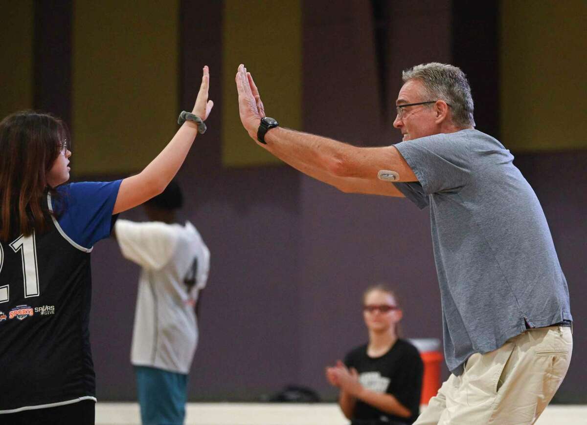 R.C. Buford, chief executive officer of Spurs Sports & Entertainment, high fives a participant in the Spurs Inclusive Sports League at Morgan’s Wonderland on Wednesday, Aug. 17, 2022. The Spurs 2022 draft class of Jeremy Sochan, Malaki Branham and Blake Wesley joined coaches from Our Lady of the Lake University and others in a night of basketball for the children.