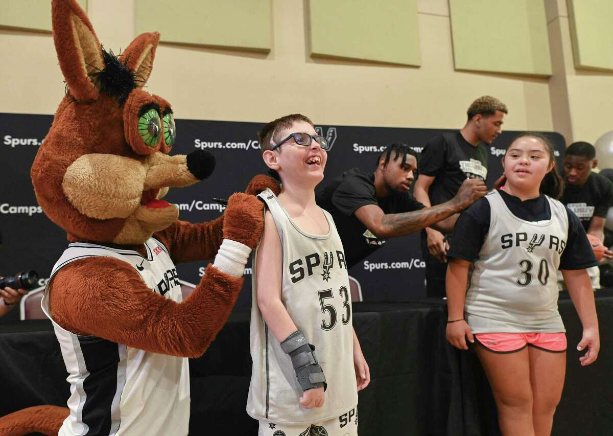 Benjamin Kelley (53) and Olivia Garza (30) have their Spurs signed basketball shirts Coyote, left, and Spurs draft pick Blake Wesley, background, on a night of children's basketball in the Spurs Inclusive Sports League at Morgan's Wonderland on Wednesday August 17, 2022.