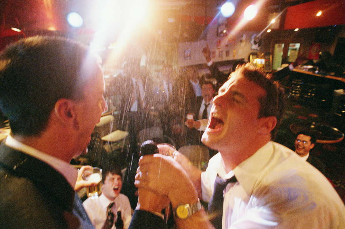 Two businessmen singing on stage at a karaoke bar. 