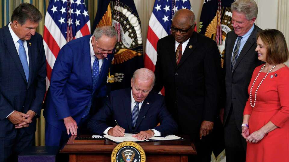 Surrounded by Democratic members of Congress, President Joe Biden signs into law the Inflation Reduction Act in the State Dining Room at the White House on Tuesday, Aug. 16, 2022, in Washington, D.C. (Yuri Gripas/Abaca Press/TNS)