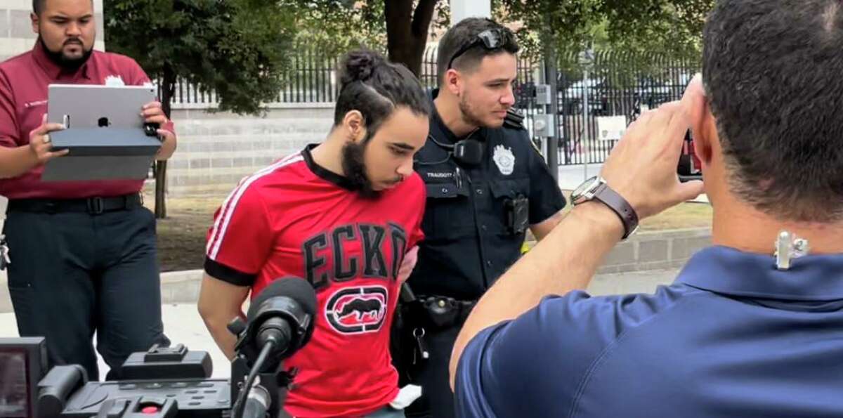 Pedro Luis Carrero, 18, one of three siblings arrested Thursday, is led to a squad car outside the Bexar County Sheriff’s Office. He is charged with injury of a disabled person by neglect causing serious bodily injury, according to the Sheriff's Office.