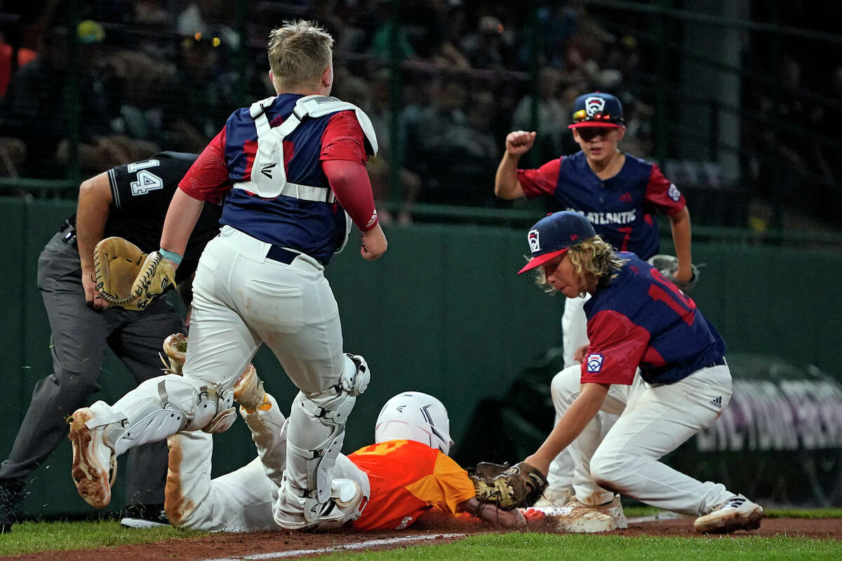 Hollidaysburg, Pa.'s Chase Link (18) applies a tag on Pearland, Texas' Kaiden Shelton, center, who slides back safely into third to end a rundown during the fifth inning of a baseball game at the Little League World Series in South Williamsport, Pa., Thursday, Aug. 18, 2022. (AP Photo/Gene J. Puskar)