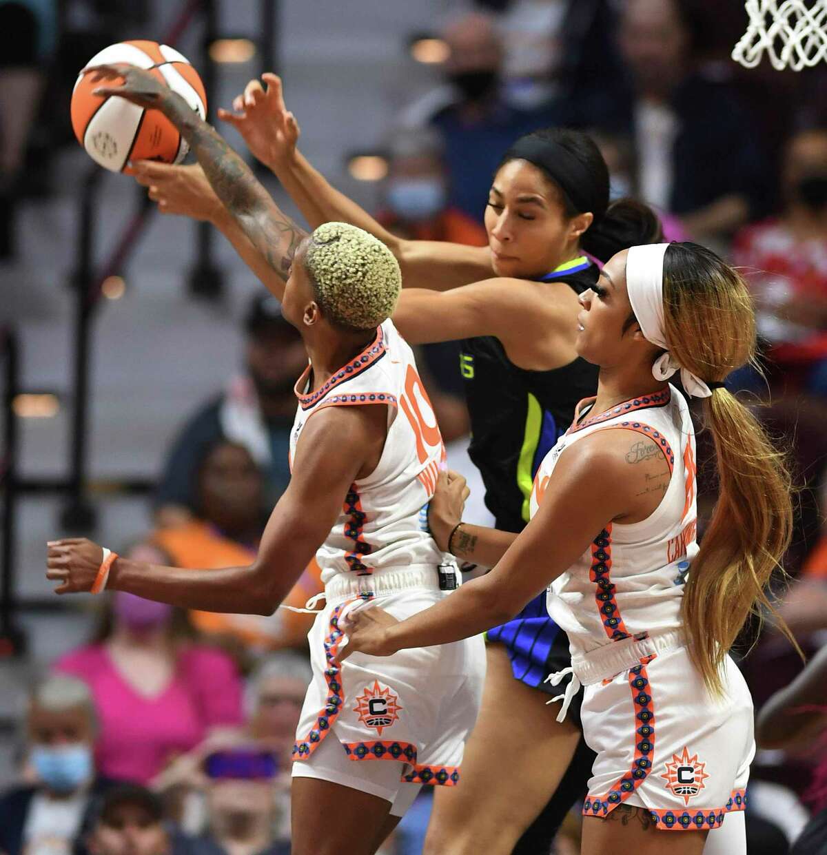 Connecticut Sun guard Courtney Williams (10) and forward DiJonai Carrington, right, battle against Dallas Wings forward Kayla Thornton, center, for a rebound during Game 1 of a WNBA basketball first-round playoff series Thursday, Aug. 18, 2022, in Uncasville, Conn. (Sean D. Elliot/The Day via AP)